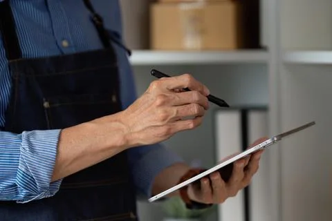 Small business owner taking notes on a tablet while managing tasks in a startup Foto stock