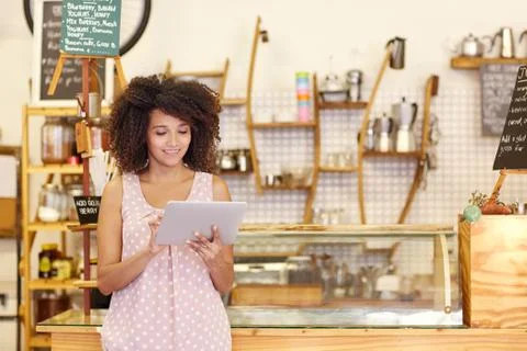 Small business owner using a tablet in her coffee shop Stock Photos
