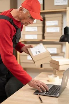 Small business startup worker using laptop in warehouse with boxes and parc.. Stock Photos