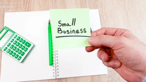 Small business text on a sheet of notes in the hands of a businessman at a desk Stock Footage 279694440