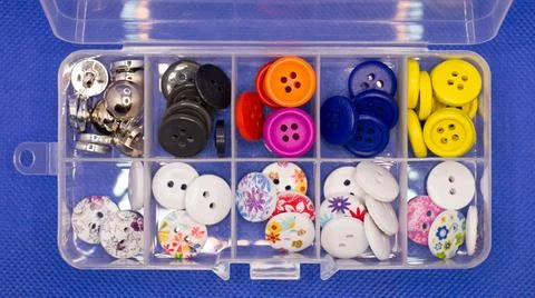 Small buttons for clothes of different types lie cells of a plastic container Stock Photos