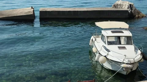 Small cabin boat is moored beside a concrete pier in clear water of Bay of Kotor Stock Footage 344904672