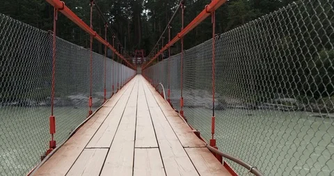 Small cable-stayed suspension bridge over mountain river sway under gusts wind Stock Footage 118297574