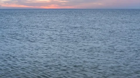 Small calm ocean waves with horizon and beautiful sunset sky - water background Stock Footage 143524625