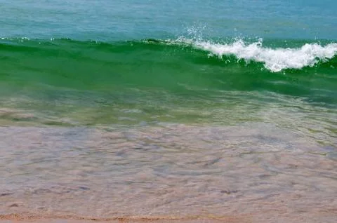 Small calm wave on sandy beach Stock Photos