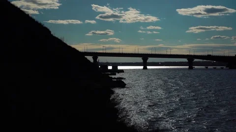 Small calm waves moving slowly as cars drive on big bridge across river under Stock-Footage 107335120
