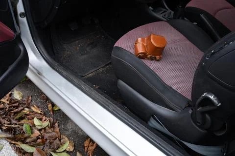 Small camera in leather case on the driver seat of a car Stock Photos
