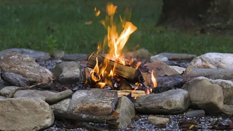 Small campfire burning hot in a backyard fire ring made from river rocks Stock Footage 342091888