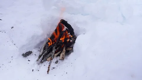 A small campfire made of wooden logs burning brightly on snow. The fire cre.. Stock Footage 287073258