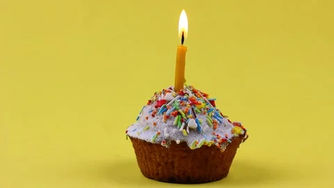 A small candle burns in an Easter cupcake, anointed with white glaze and Stock Footage 146717044