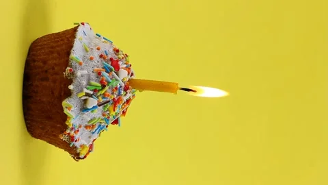 Small candle burns in an Easter cupcake, anointed with white glaze and sprinkled Stock Footage 147905899