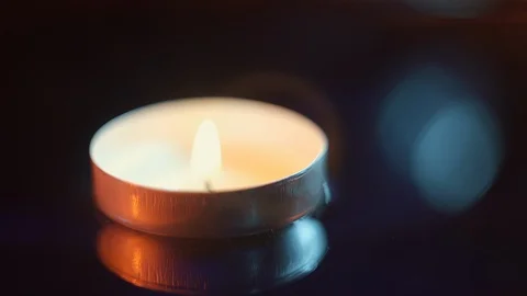 A small candle floating in the water in the darkness illuminated with warm tones Stock Footage 114066795