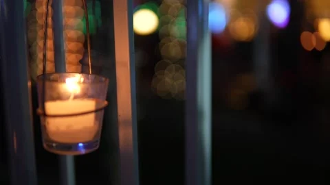 Small candle glowing inside a glass holder at night time Stock Footage 335270766