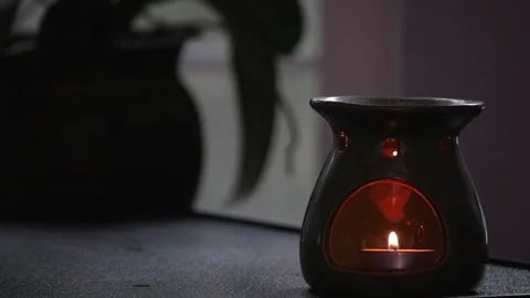 Small candle lit on the inside of an essential oil burner Stock Footage 152939542