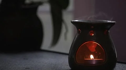 Small candle lit on the inside of an essential oil burner Stock Footage 152939639