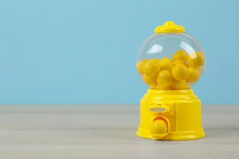 Small candy machine with lemon chewing gums on wooden table, space for text Stock Photos