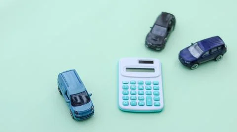 Small car models sit next to a calculator, symbolizing financial planning, .. Stock Photos