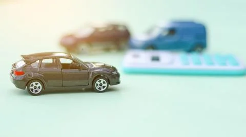 Small car models sit next to a calculator, symbolizing financial planning, .. Stock Photos