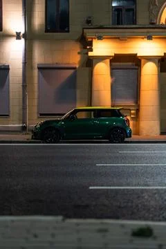 Small car is parked on the side of the road, at night in the city Stock Photos