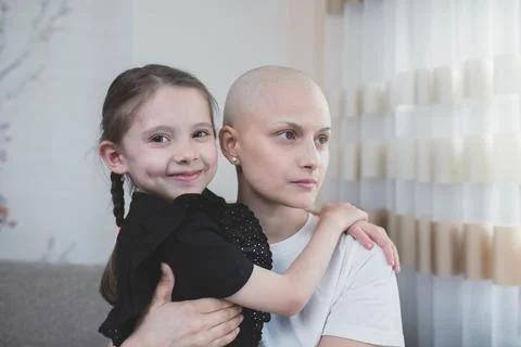Small caring child embracing her ill bald mother after chemotherapy Stock Photos