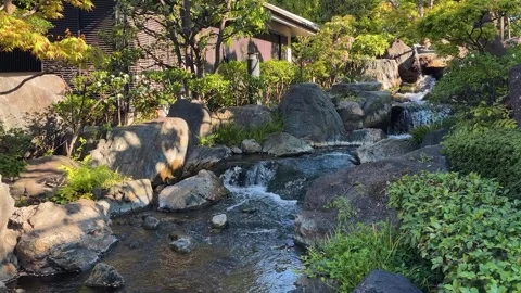 A small cascade waterfall flows over large rocks in Mejiro Garden. Stock Footage 335695603