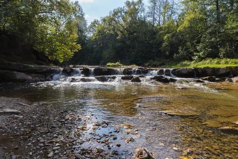 Small cascade waterfall on a mountain river in sunny day Stock Photos