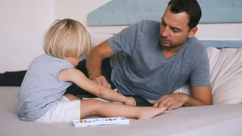 A small caucasian boy with his father on the bed draw with colored pencils. Stock Footage 220731759