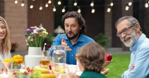 Small Caucasian boy sitting at table outdoors at back yard with parents and Stock Footage 144197139