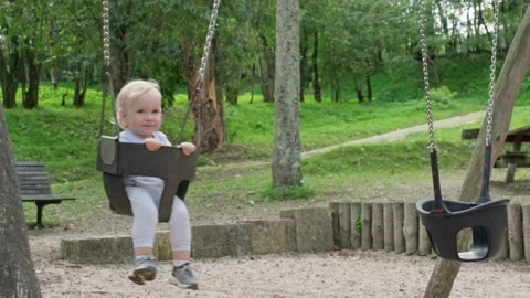 Small caucasian Child having fun swinging on a swing on the kid's playgroun.. Stock Footage 253643384