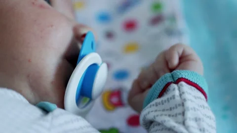 A small caucasian child sucks on a bare pacifier, the focus shifts from the Stock-Footage 295103953