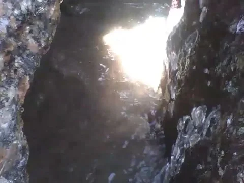 A small cave on the beach in the rocks, receives water from sea and sun Stock Footage 163684887