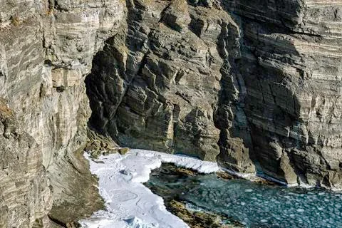 Small cave in a rock winter view with snow and ice floes in the sea Stock Photos