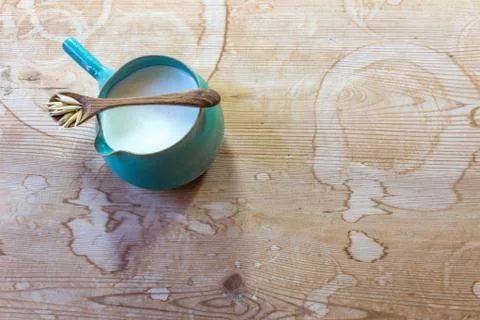 Small ceramic pitcher of oat milk with wooden spoon and oats, copy space Stock Photos