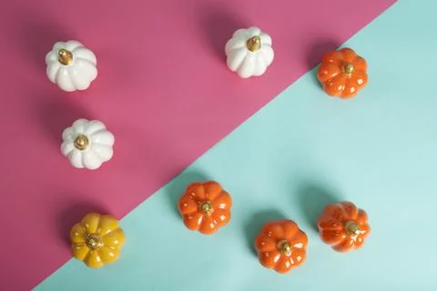 Small ceramic pumpkins in different colors on a two-tone turquoise and fusc.. Stock Photos