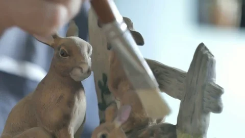Small ceramic rabbits being dusted with a paint brush Not B&amp;W Vidéo 72766299