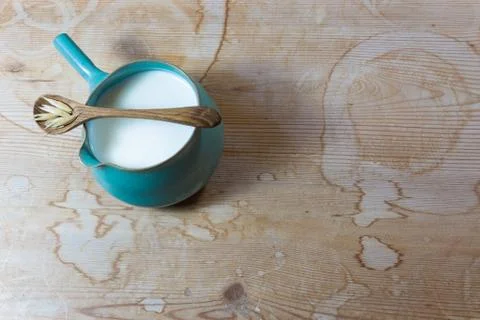 Small ceramic side handle pitcher filled with oat milk, wooden spoon oats Stock Photos