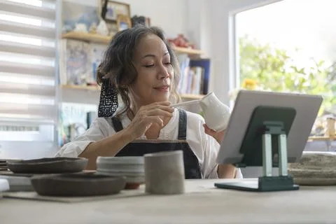 Small ceramic studio owner holding pottery earthenware product in front of di Stock Photos
