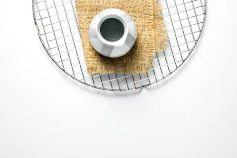 A small ceramic teapot is photographed with a burlap base on a cake dryer net Stock Photos