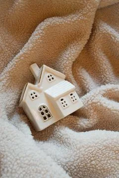 Small ceramic winter house on fluffy soft sheep blanket Stock Photos