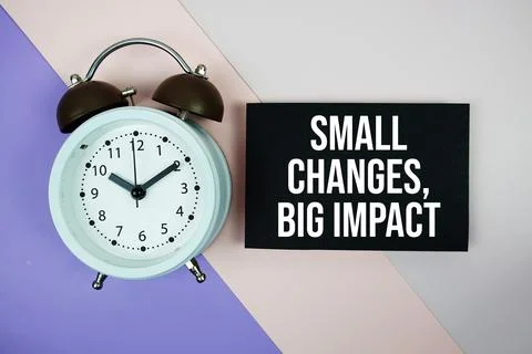 Small Changes, Big Impact text on paper card with alarm clock on purple and.. Stock Photos