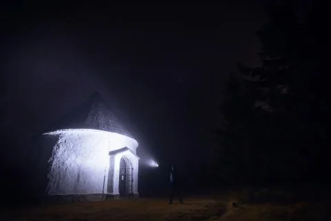 Small chapel lighten by man with flashlight in foggy evening in Czechia Stock Photos