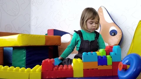 A small charming girl of 4-5 years is building something from multi-colored p Stock Footage 80667584