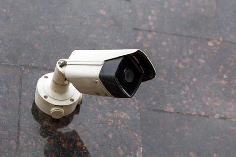 Small cheap surveillance camera on tan brown granite wall Photos
