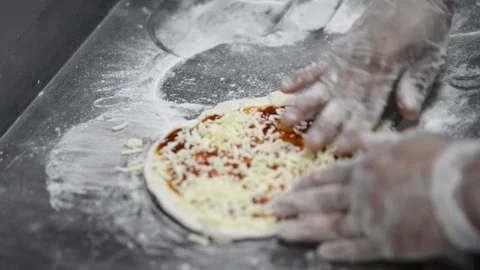 Small cheese pizza being prepared cheese being sprinkled put on Stock-Footage 169606246