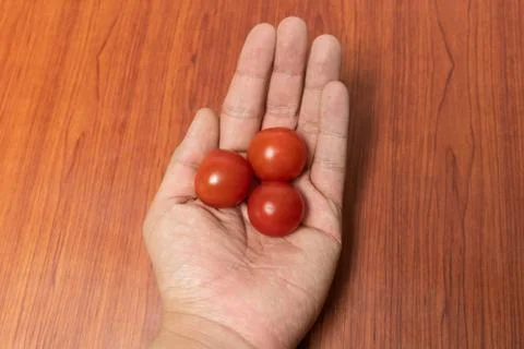 Small cherry tomato close up in the hands Foto stock