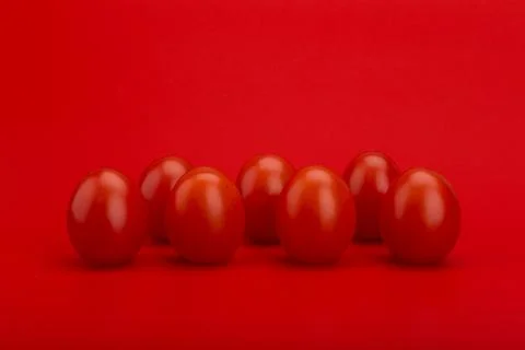 Small cherry tomatoes in a row on red background Stock Photos