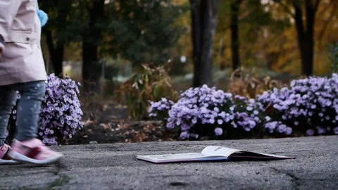 Small child 2 years old found a book on the sidewalk Stock Footage 131457550