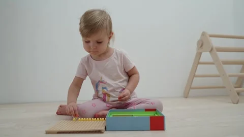 A small child 2.5 years old plays with mosaic, laying it out on a substrate. Video stock 263810563