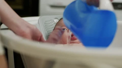 Small child bathes in bathroom before going to bed, mother pours water on him Stock Footage 194826314