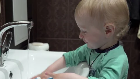 A small child, a boy, brushes his teeth on his own, early in the morning in the Stock Footage 130726269